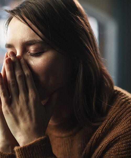 femme les yeux fermés les mains sur le visage