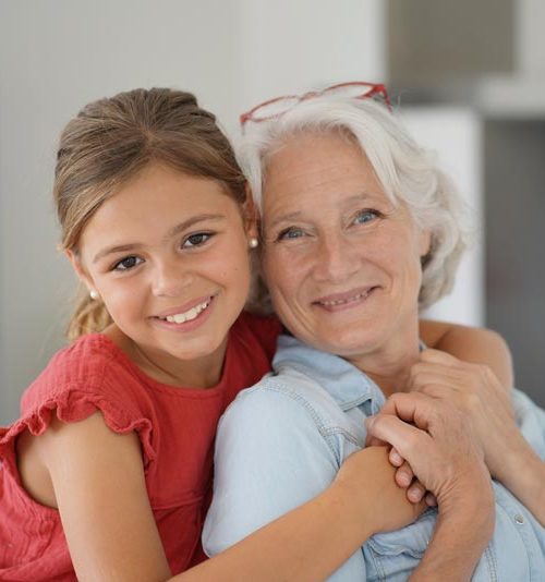 Petite fille et sa grand-mère souriant face caméra