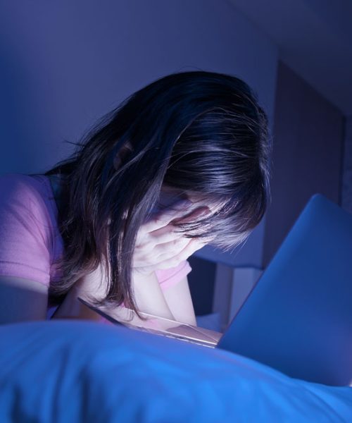 Jeune femme se cachant le visage devant son ordinateur