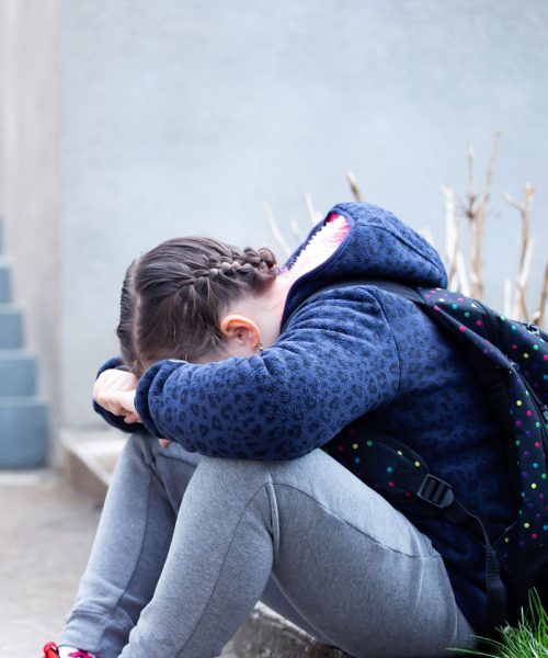 Jeune fille isolée dans la cour de son école